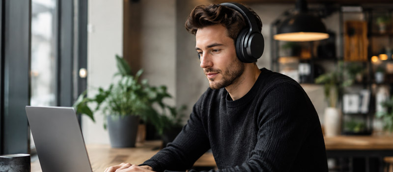Persona usando audífonos con cancelación de ruido mientras trabaja en una laptop